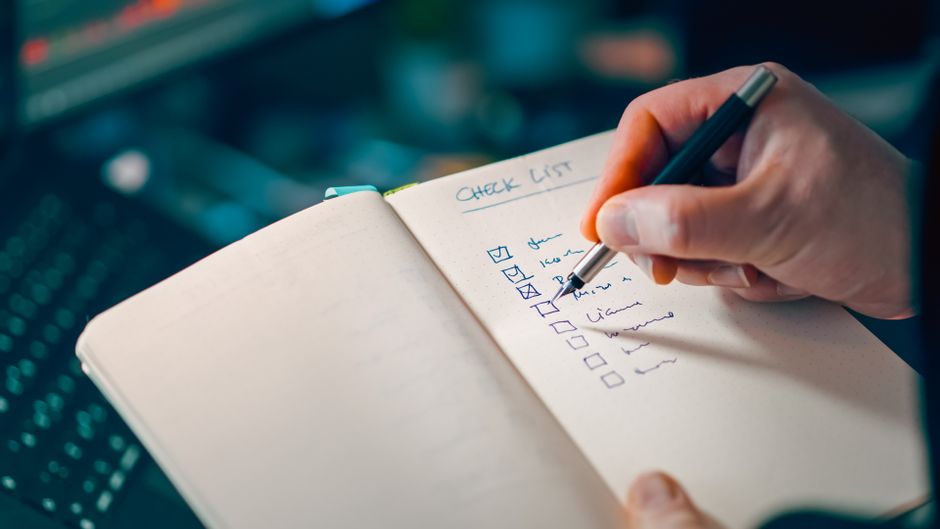 Hand checking off items on a printable subscription audit checklist