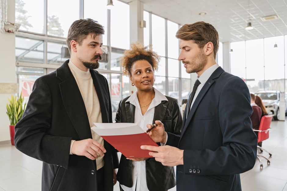 person signing loan paperwork at a car dealership