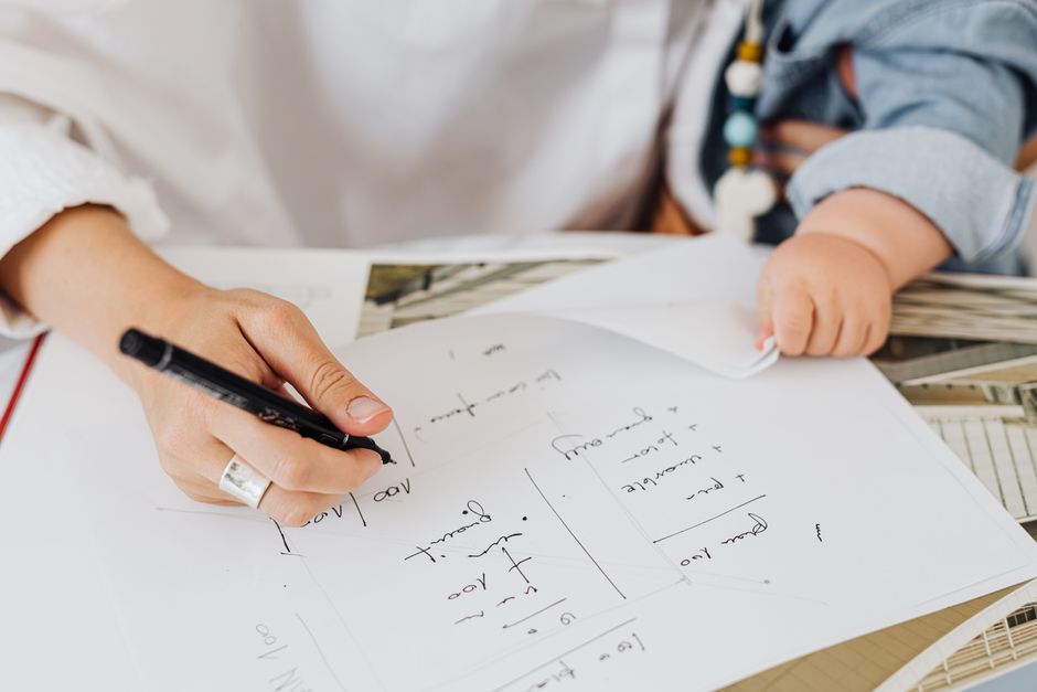 Parent filling out tax forms at a kitchen table with a child nearby