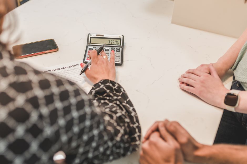 Hands calculating downsizing costs with a calculator and small house model