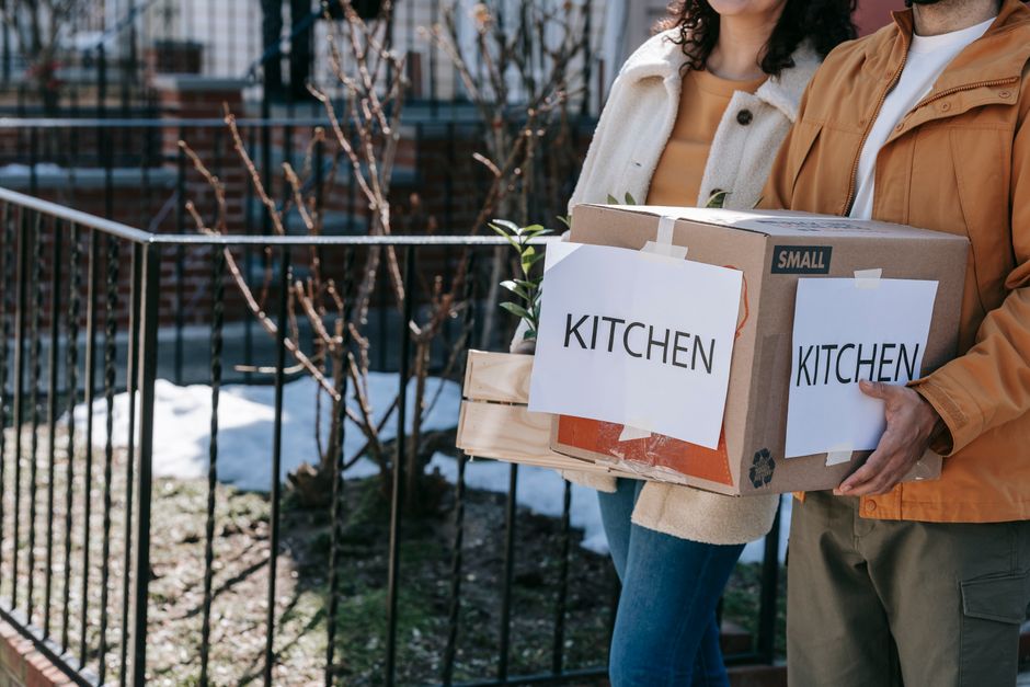 Retired couple sorting moving boxes outside a smaller home