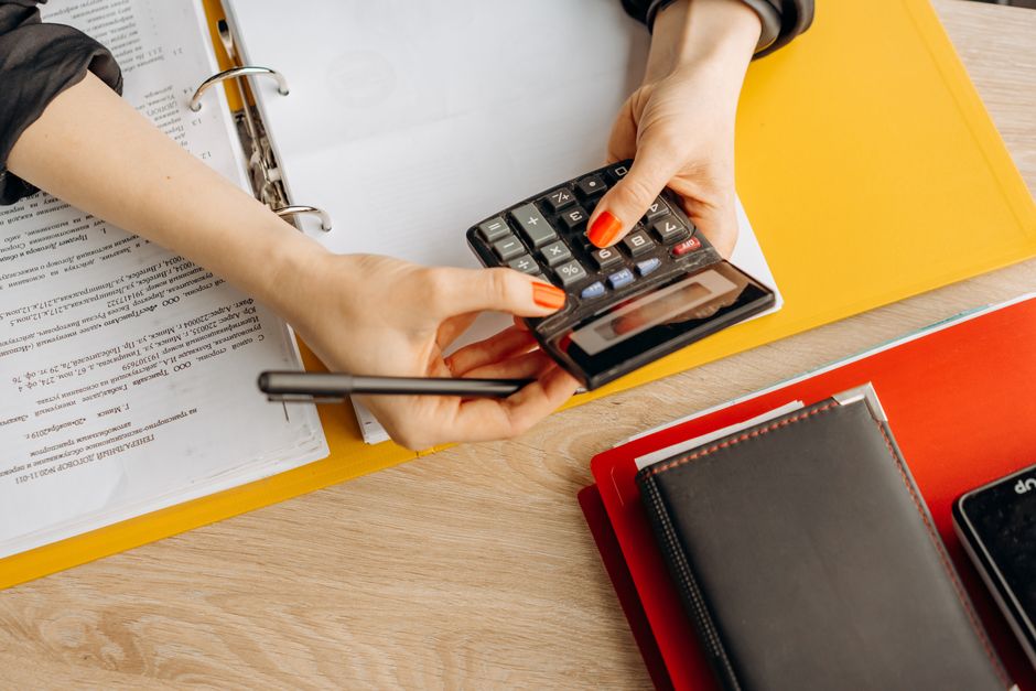 hands using a calculator next to income statements