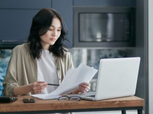 person reviewing tax documents on a laptop at a kitchen table