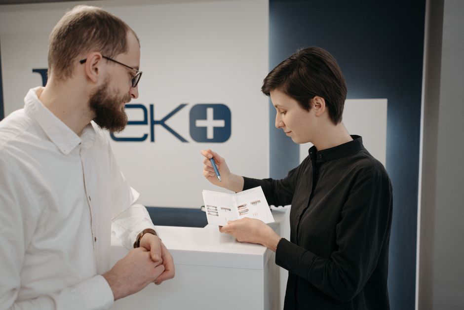 person filling out paperwork at a Medicaid office counter while speaking with a caseworker