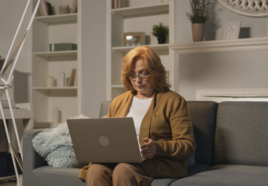 Older adult filling out an online form on a laptop at home