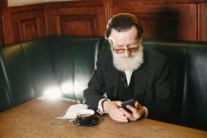 older adult reviewing a phone bill on a smartphone at the kitchen table