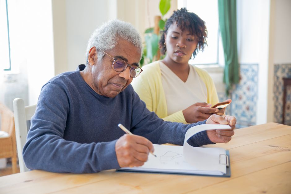 older adult filling out a benefits enrollment form with help from a family member