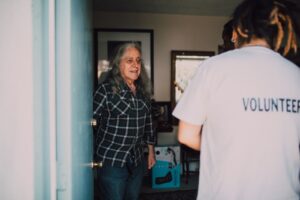 volunteer delivering a meal to an older adult at their front door
