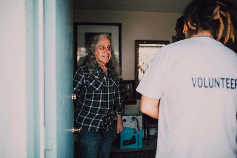 volunteer delivering a meal to an older adult at their front door
