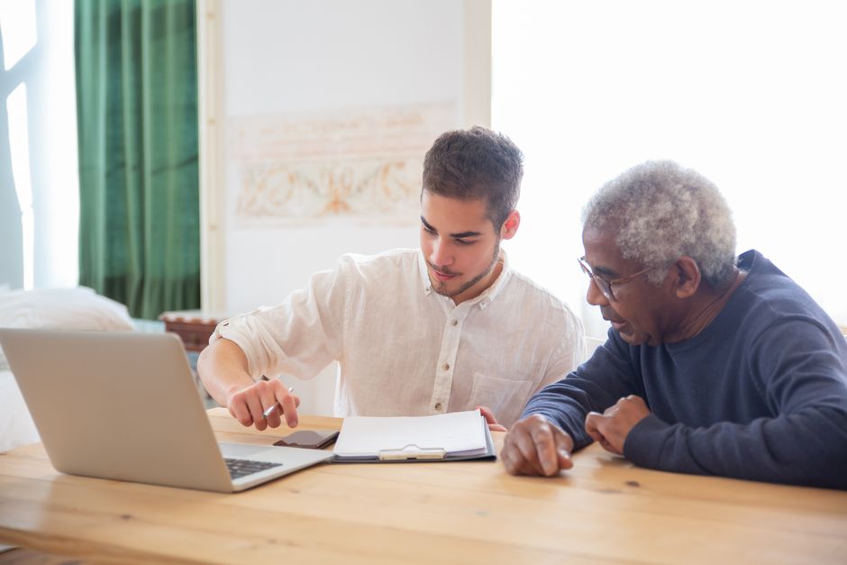adult child helping an elderly parent look up meal delivery services on a laptop