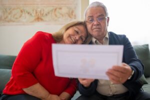 Older homeowner couple reviewing a property tax bill outside their home