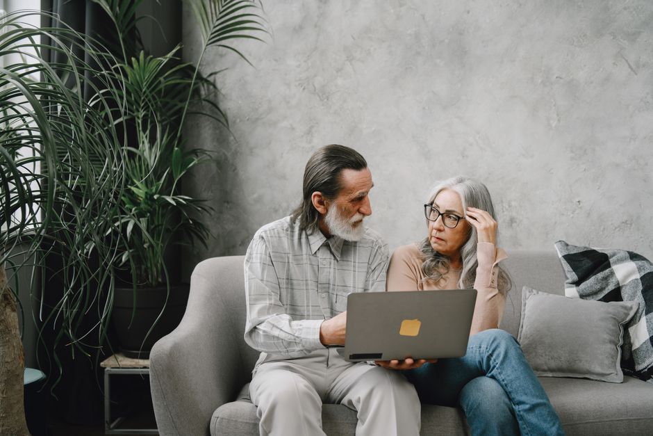 Older couple comparing cell phone plans on a laptop and phone