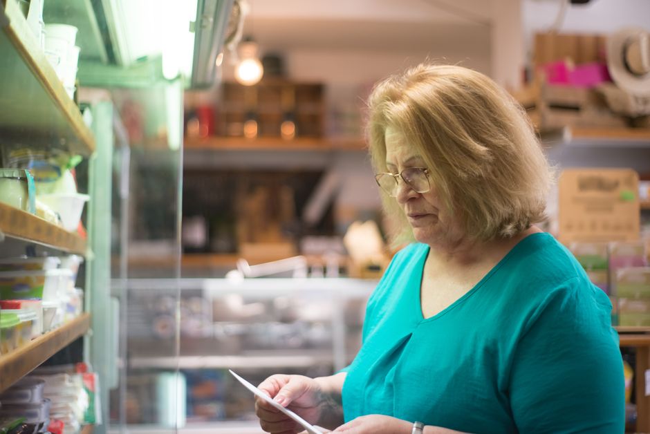 An elderly shopper looking at a senior discount sign at a grocery store