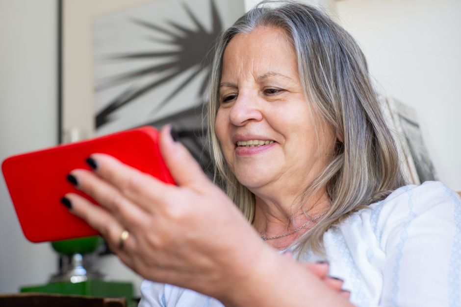 Happy senior woman using her smartphone, representing savings on her monthly phone bill