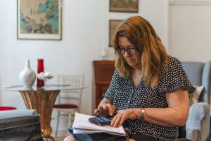 Senior woman reviewing SSA application paperwork and calculating monthly expenses with a calculator