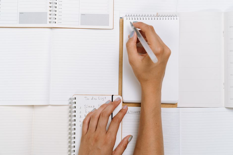 Hands writing a grocery shopping list planned around a senior discount day