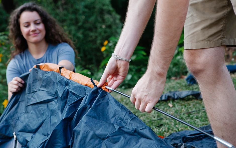Couple pitching a tent together at a campground