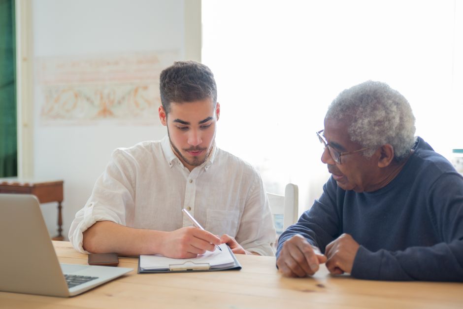 Adult child reviewing tax paperwork with an elderly parent at home