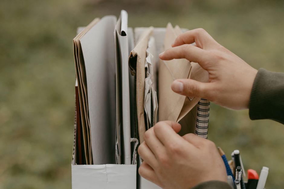 Hands organizing medical receipts and tax forms in a folder for filing