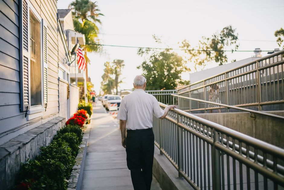 Senior man wearing a mobile GPS medical alert pendant while walking outdoors