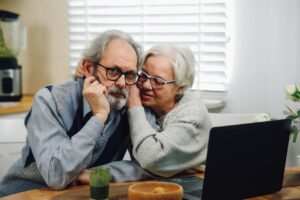Senior couple reviewing Medigap insurance documents and comparing plans on a laptop at home