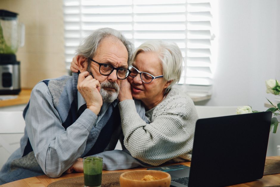 Senior couple reviewing Medigap insurance documents and comparing plans on a laptop at home