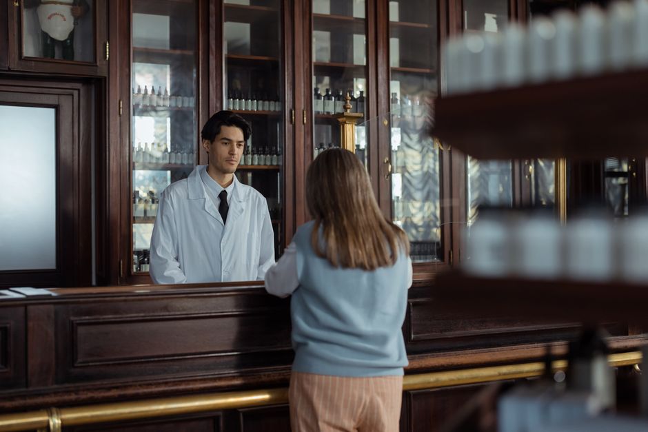 Senior customer talking with a pharmacist at a pharmacy counter