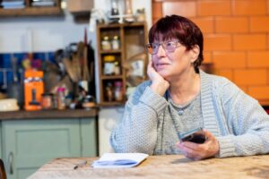 senior woman checking a grocery delivery app on a tablet at her kitchen table