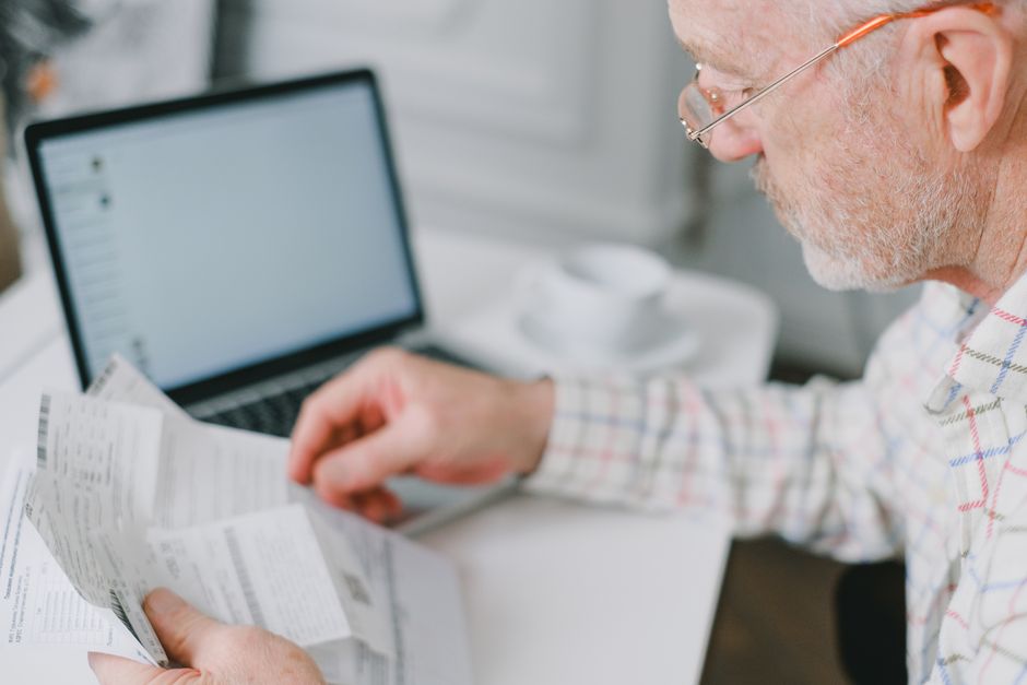 grandfather organizing paperwork and documents at home office desk