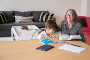 grandmother helping grandchild with homework at kitchen table