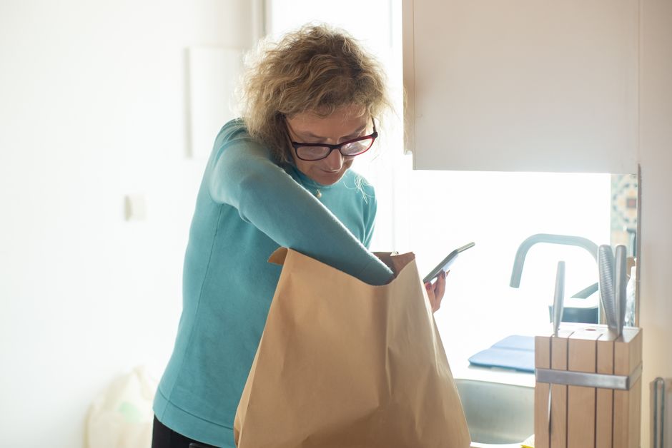 Retiree unpacking affordable grocery bags in kitchen