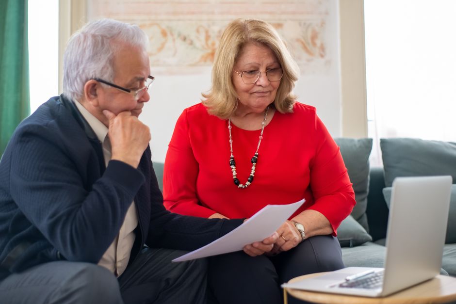 senior couple reviewing homeowners insurance policy documents outside their home