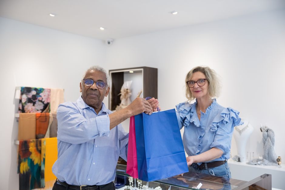 Senior couple smiling while leaving a retail store with shopping bags