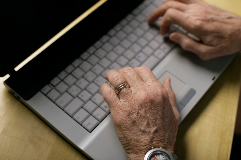 Senior traveler's hands booking a train ticket on a laptop website