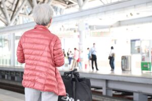 Senior traveler with luggage waiting for a train on a station platform