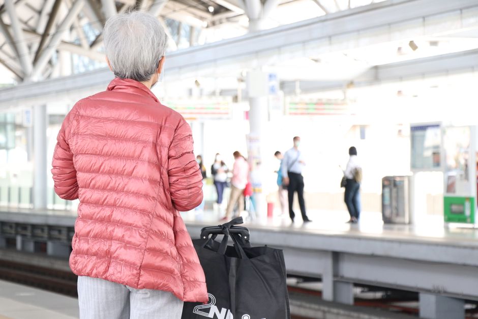 Senior traveler with luggage waiting for a train on a station platform