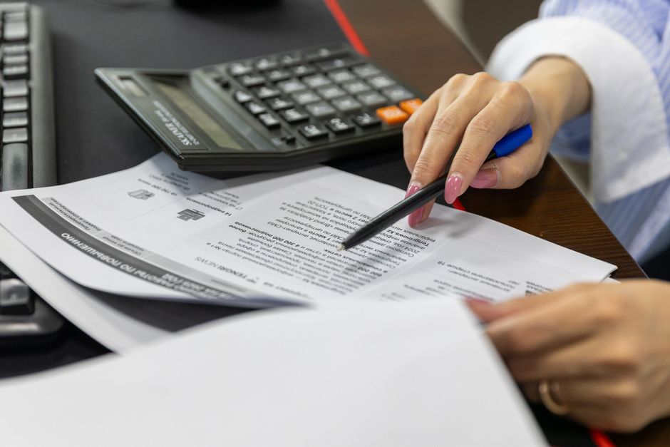 Close-up of hands reviewing a CCRC contract with paperwork and a calculator on the desk