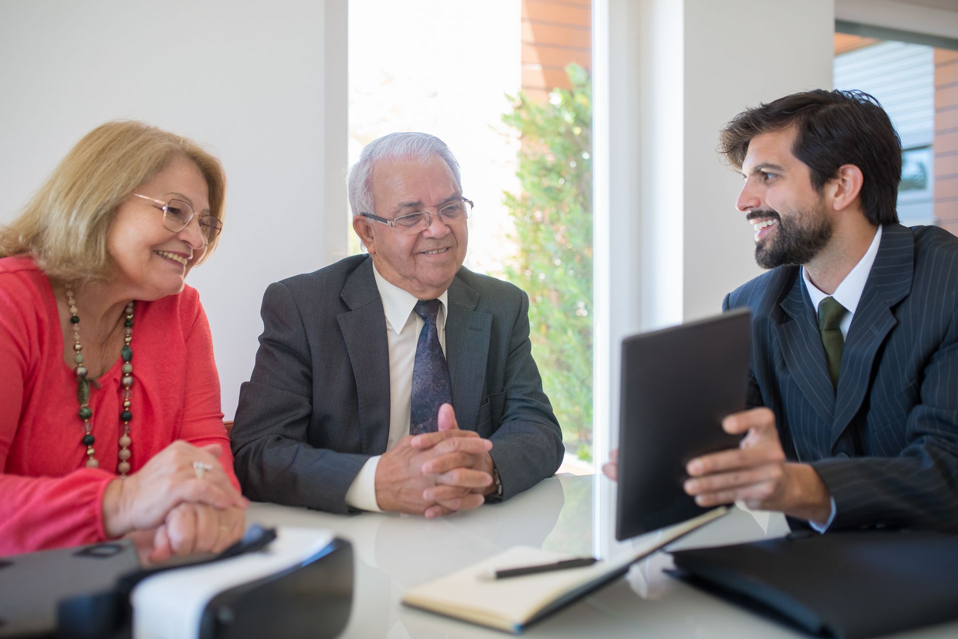 Older couple smiling while speaking with an advisor in an office setting