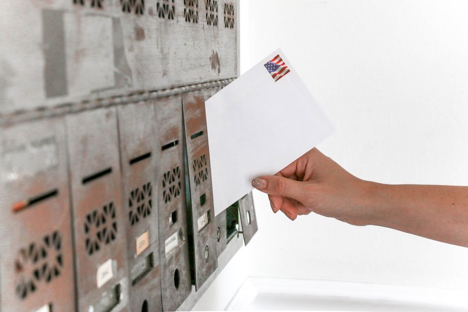 Hand retrieving a government benefit payment envelope from a Canadian mailbox
