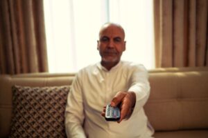 Retiree using a remote control to choose a streaming service at home