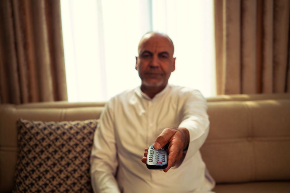 Retiree using a remote control to choose a streaming service at home