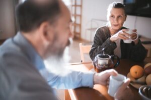 Retired homeowner and housemate having coffee together in a shared living room