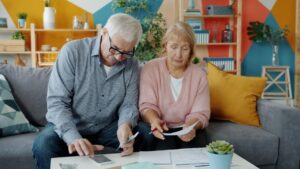 Retired couple reviewing financial documents and a calculator at home