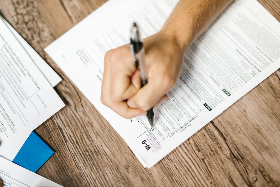 Hands submitting a property tax relief application form at a county trustee office