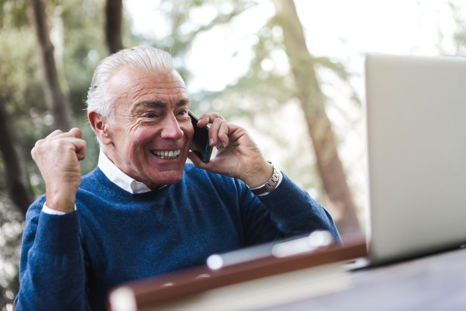 Retired man on the phone with his insurer while using a laptop