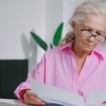 Older woman reviewing Medicare paperwork at a kitchen table