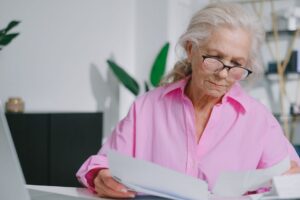 Older woman reviewing Medicare paperwork at a kitchen table