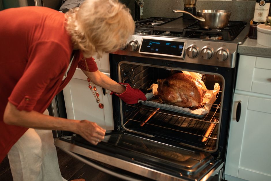 Senior woman checking a turkey roasting in the oven